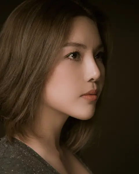 Sample frame: Woman with a bob haircut against an olive wall