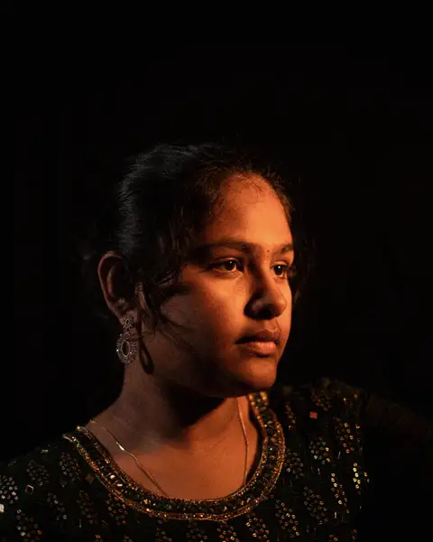 Sample frame: Woman in warm side light against a dark wall