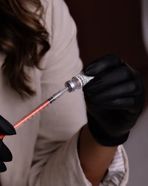 Injector in black gloves holding a fine syringe